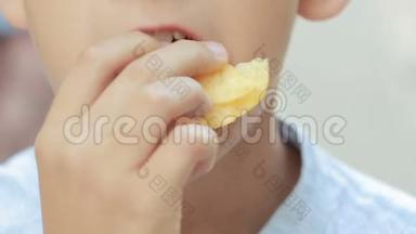 在街上吃薯片的男孩。 小男孩吃垃圾食品